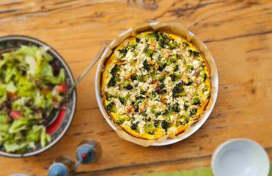 essenzielles Rezept des Monats Quiche mit buntem Salat auf Holztisch